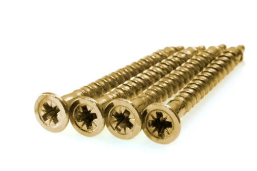 Four copper-colored screws on white background with soft shadow.