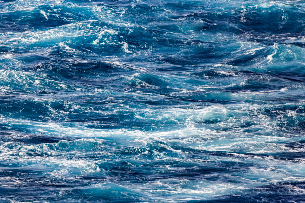 Blue deep sea foaming water background Foaming water from the back of a ship spume stock pictures, royalty-free photos & images