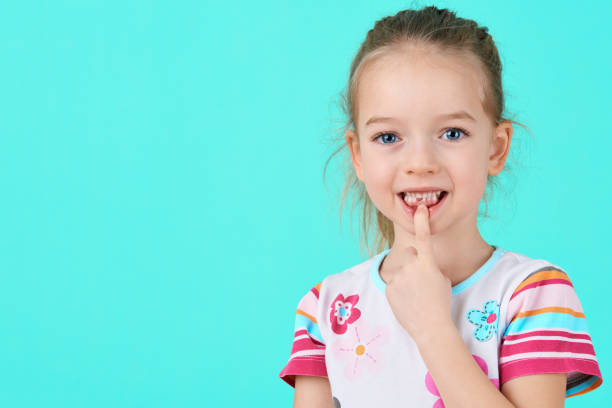 adorable petite fille souriante et exhibant sa première dent de lait perdue. portrait de mignon bambin après avoir abandonné sa dent de bébé avant. - hygiene dental hygiene human teeth child photos et images de collection