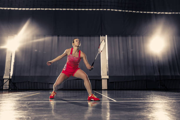 jovem mulher jogando badminton no ginásio - badminton school gymnasium shuttlecock sport - fotografias e filmes do acervo