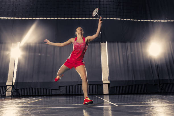 jovem mulher jogando badminton no ginásio - badminton school gymnasium shuttlecock sport - fotografias e filmes do acervo