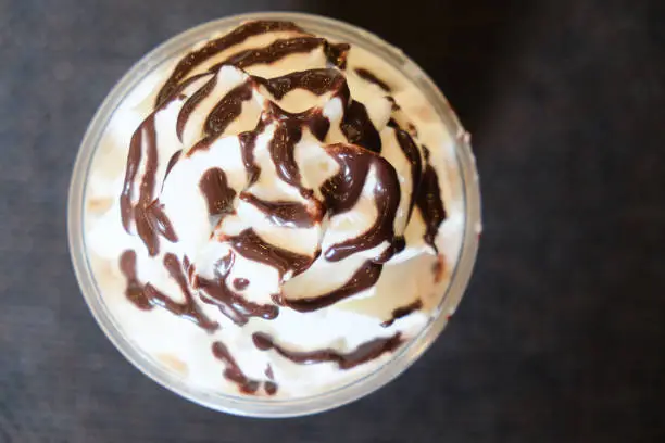 Drink covered with whipped cream and chocolate sauce, top view