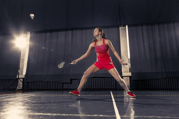 jovem mulher jogando badminton no ginásio - badminton school gymnasium shuttlecock sport - fotografias e filmes do acervo