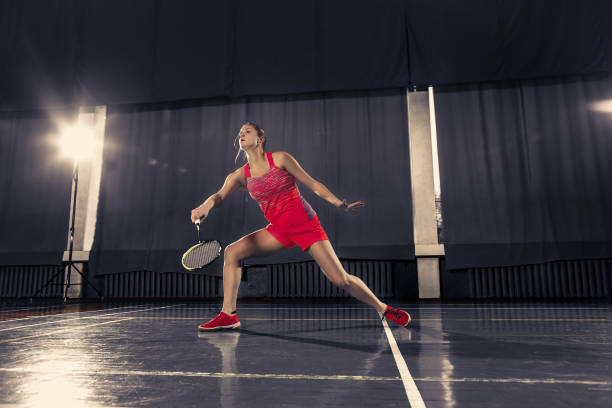 jovem mulher jogando badminton no ginásio - badminton school gymnasium shuttlecock sport - fotografias e filmes do acervo