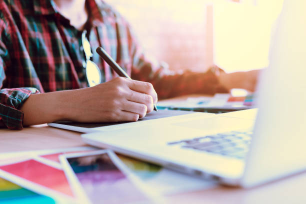 istock Freelance creative designers working on desk using digital graphic tablet and drawing with pen in modern home office. 912167200