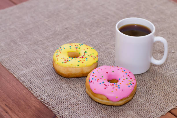 istock Donuts with icing on the table. Nearby is a mug with coffee. Sweet colored donuts 912167546