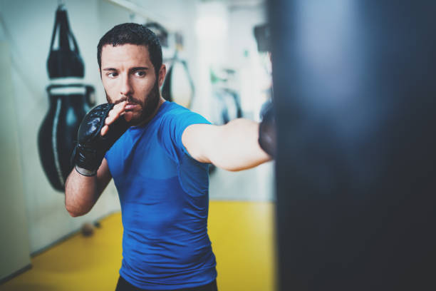istock Young muscular kickboxing fighter practicing kicks with punching bag.Boxing on blurred background.Concept of a healthy lifestyle.Horizontal. 912167936