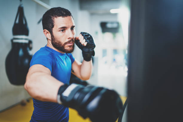 istock Young muscular kickboxing fighter practicing kicks with punching bag.Kick boxer boxing as exercise for the fight.Boxer hits punching bag.Concept of a healthy lifestyle.Horizontal. 912170952