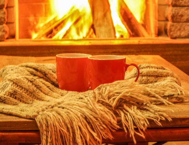 istock Two colorful mugs for tea or coffee, wool things near cozy fireplace . 912171148