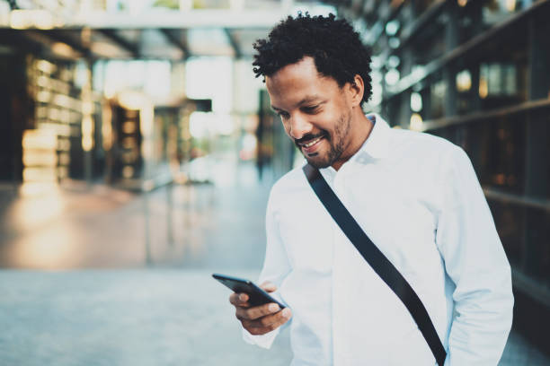 istock Smiling African American man holding mobile phone in hands and checking email.Blurred background. 912171660