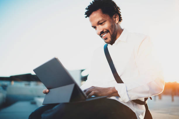 istock Happy African American man sending email via electronic touch pad pro holding in hands.Concept of guy using Internet-enabled electronic device outside.Blurred background. 912174048