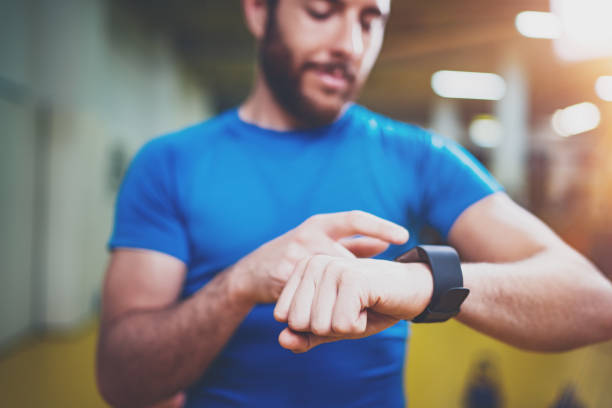 istock Young Muscular bearded athlete checking burned calories on electronic smart watch application after good indoor workout session in fitness gym.Blurred background. 912177396