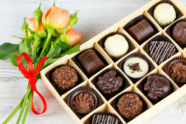 ramo de hermosas rosas y caja de chocolate en la superficie de madera - orange rose candy valentines day fotografías e imágenes de stock