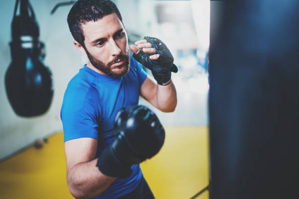 istock Young boxer doing some training on punching bag at gym. Bearded caucasian boxer training with punching bag in gym.Concept of a healthy lifestyle.Horizontal. 912181404