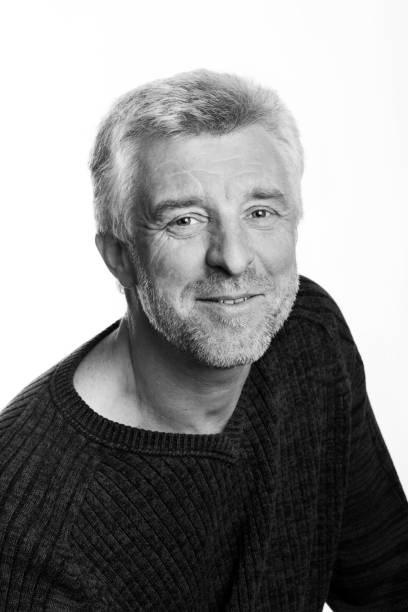 istock older gray-haired man sitting smiling looking at the camera grey eyes 912207784
