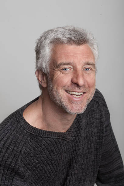 istock older gray-haired man sitting smiling looking at the camera grey eyes 912207804