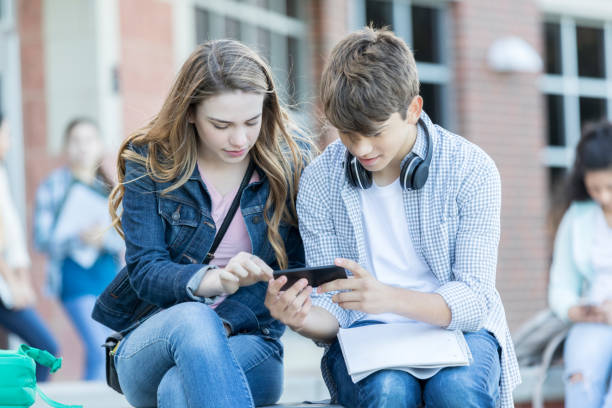 istock High school couple look at smart phone together 912208342