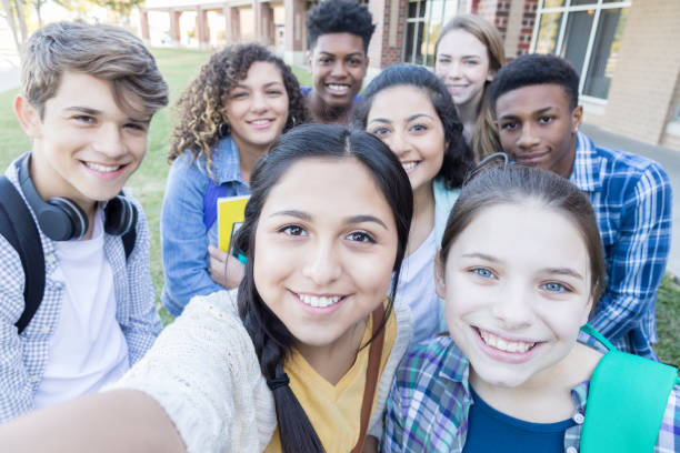 Group of high school friends take selfie together Multi-ethnic group of teenagers take a selfie together before school. They are outdoors on the high school campus. teenagers only stock pictures, royalty-free photos & images