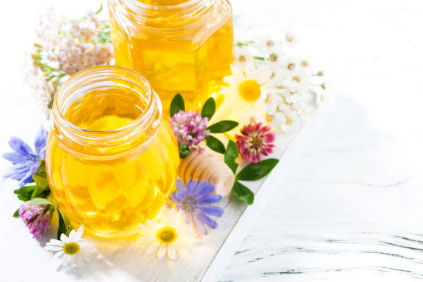 istock jars with flower honey on white wooden background, top view 912208440