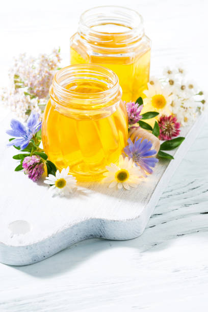 istock jars with fresh flower honey on white board, vertical 912208650