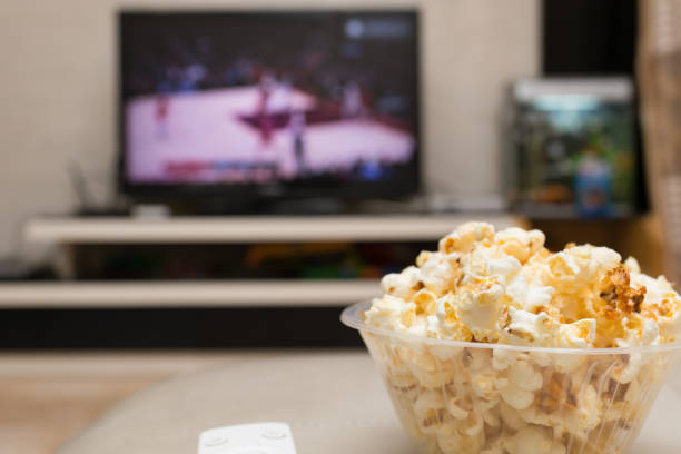 palomitas y mando a distancia en el sofá con un baloncesto de difusión de tv coinciden en el fondo - vegetable basket fotografías e imágenes de stock