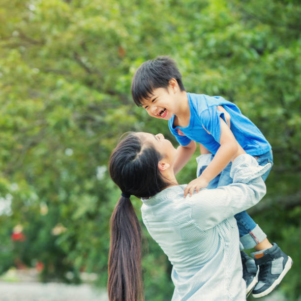 istock Playful mom lifts young son while playing outdoors 912208854