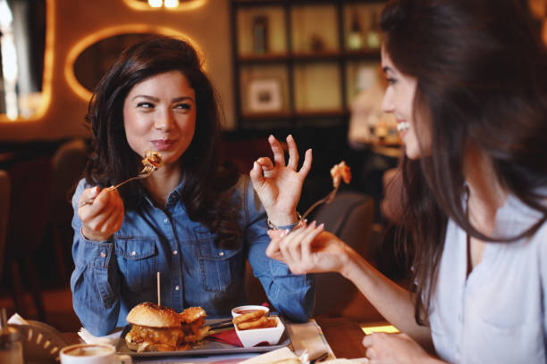 zwei junge frauen bei einem mittagessen in einem restaurant - essen am tisch stock-fotos und bilder