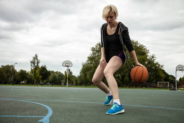 frau spielt korb am basketballplatz in hackney - london - uk - hackney stock-fotos und bilder