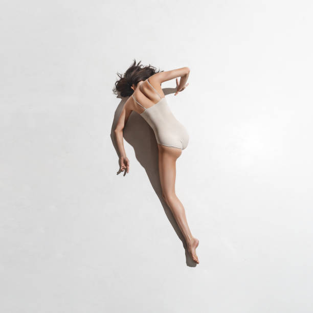 istock Young beautiful dancer in beige dress dancing on gray background 912226438
