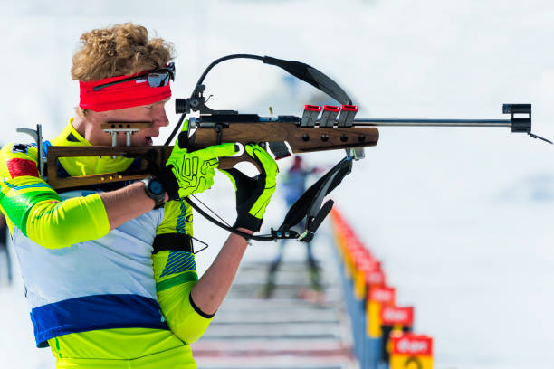 side view of young male biathlon competitor practicing at shooting range, standing position - biathlon imagens e fotografias de stock