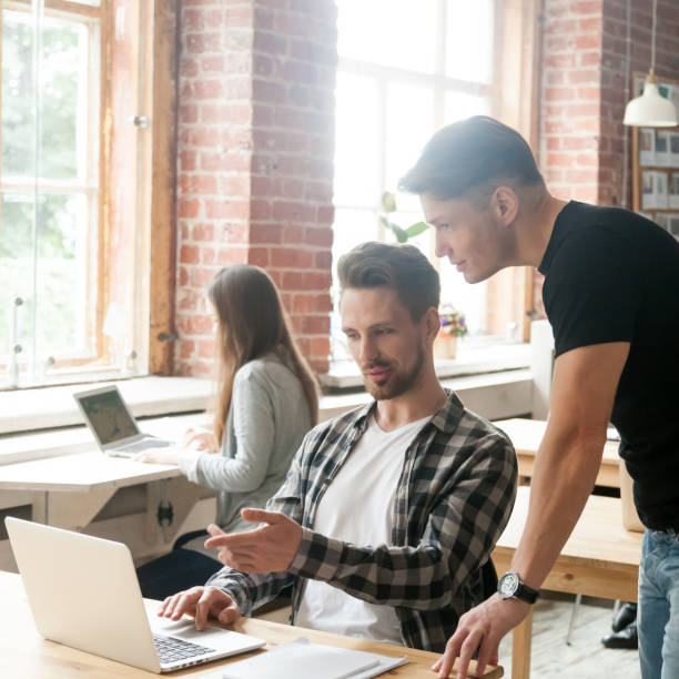 istock Businessman working on laptop, talking to colleague in co-working space 912235012
