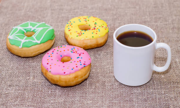 istock Donuts with icing on the table. Nearby is a mug with coffee 912235160