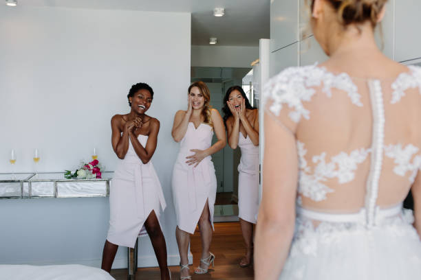 istock Surprised bridesmaids looking at bride in wedding gown 912235352