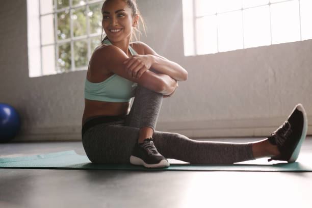 uśmiechnięta kobieta na siłowni robi sobie przerwę od treningu - stretching yoga exercise mat women zdjęcia i obrazy z banku zdjęć