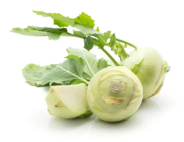 Kohlrabi (German turnip or turnip cabbage) two bulbs and one sliced quarter with fresh leaves isolated on white background