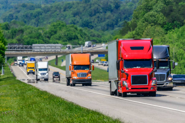 Heavy Traffic On The Interstate Highway A steady flow of semis lead the way down a busy interstate highway in Tennessee.  Heat waves rising from the pavement give a nice shimmering effect to vehicles and forest behind the lead trucks.  Excellent reverse copy space across both top and bottom of image. trucking photos stock pictures, royalty-free photos & images