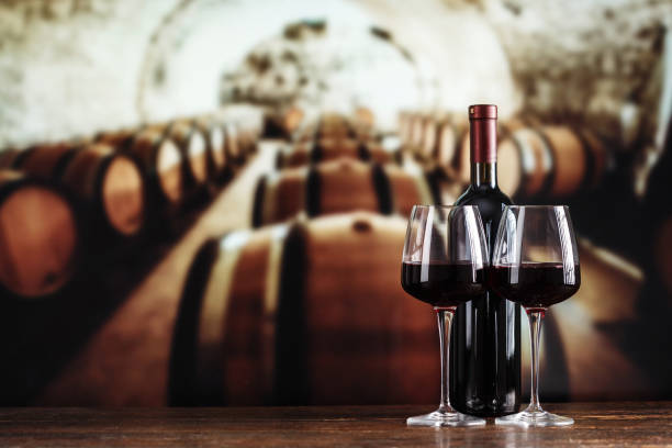 a glass and a bottle of wine on the background a glass and a bottle of wine on the background of barrels in the cellar winery stock pictures, royalty-free photos & images