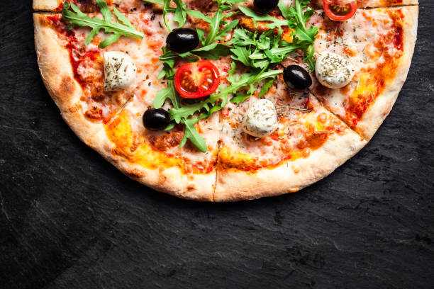 pizza con tomates, mozzarella y rúcula. menú de pizza. vista superior con espacio de copia en mesa de piedra oscuro - vegetarian pizza fotografías e imágenes de stock