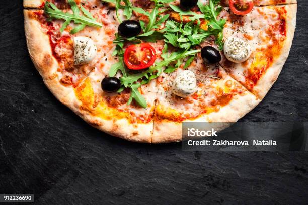 Pizza With Tomatoes Mozzarella Cheese And Arugula Pizza Menutop View With Copy Space On Dark Stone Table Stock Photo - Download Image Now