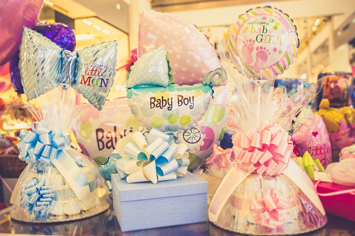 Welcome baby girl! Welcome baby boy! Colorful helium balloons and gifts for newborn birthday gift party.
