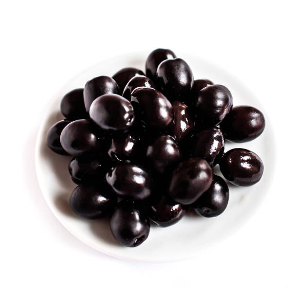 istock Whole black olives on a plate  isolated on white background. Glossy  Olive canned  fruit.  Ingredients for cooking. Top view