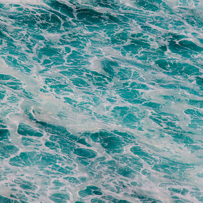 Indian ocean texture. Turquoise sea water with white foam. Powerful and peaceful nature concept.