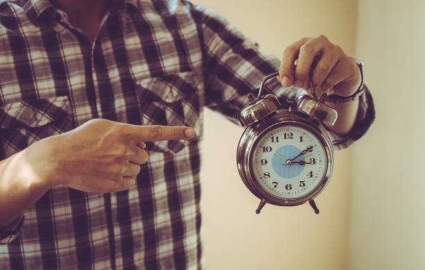 istock Man holding alarm clock point to clock to show deadline 912244602