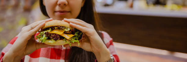 istock woman eat cheeseburger 912248816