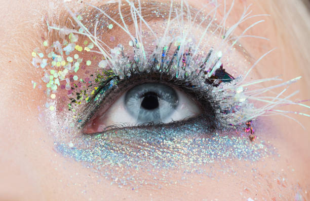 istock Winter blue eye, sparkles and glow, creative make-up. Long white false eyelashes. Cosmetics for blondes, make-up for New Year's party. Look up. Beautiful female eye 912249012