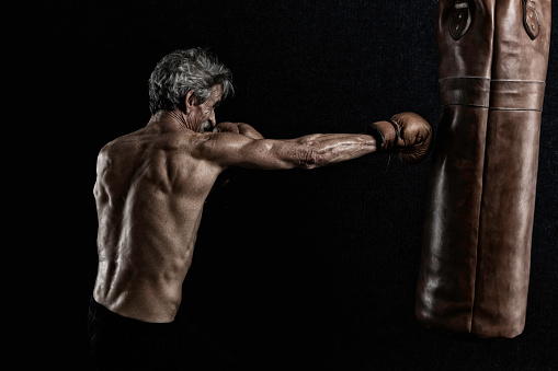 An older man covered in sweat during a workout with his punching bag.