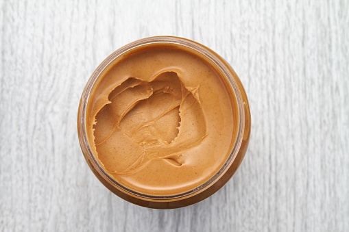Peanut butter in open jar from above on countertop