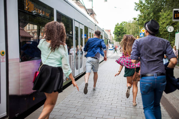 Photo of a group of young people entering a tram on a bus stop or tram stop in a city of Cracow (Kraków, Poland).