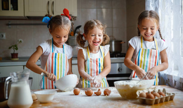 feliz hermanas niños niñas hornear galletas, amasan, jugar con harina y risa - baking lifestyles beautiful cookie fotografías e imágenes de stock