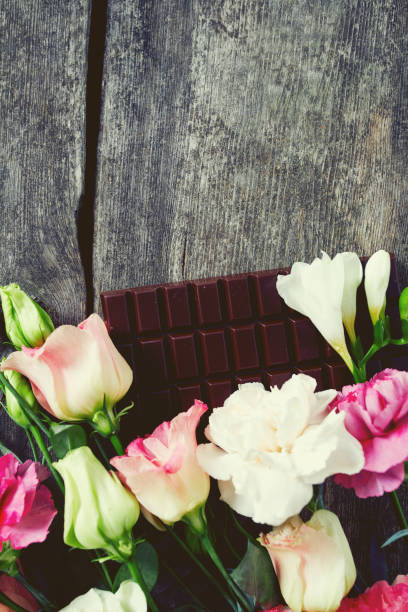 bouquet of beautiful flowers and chocolate on wooden surface - valentines day candy carnation chocolate candy imagens e fotografias de stock